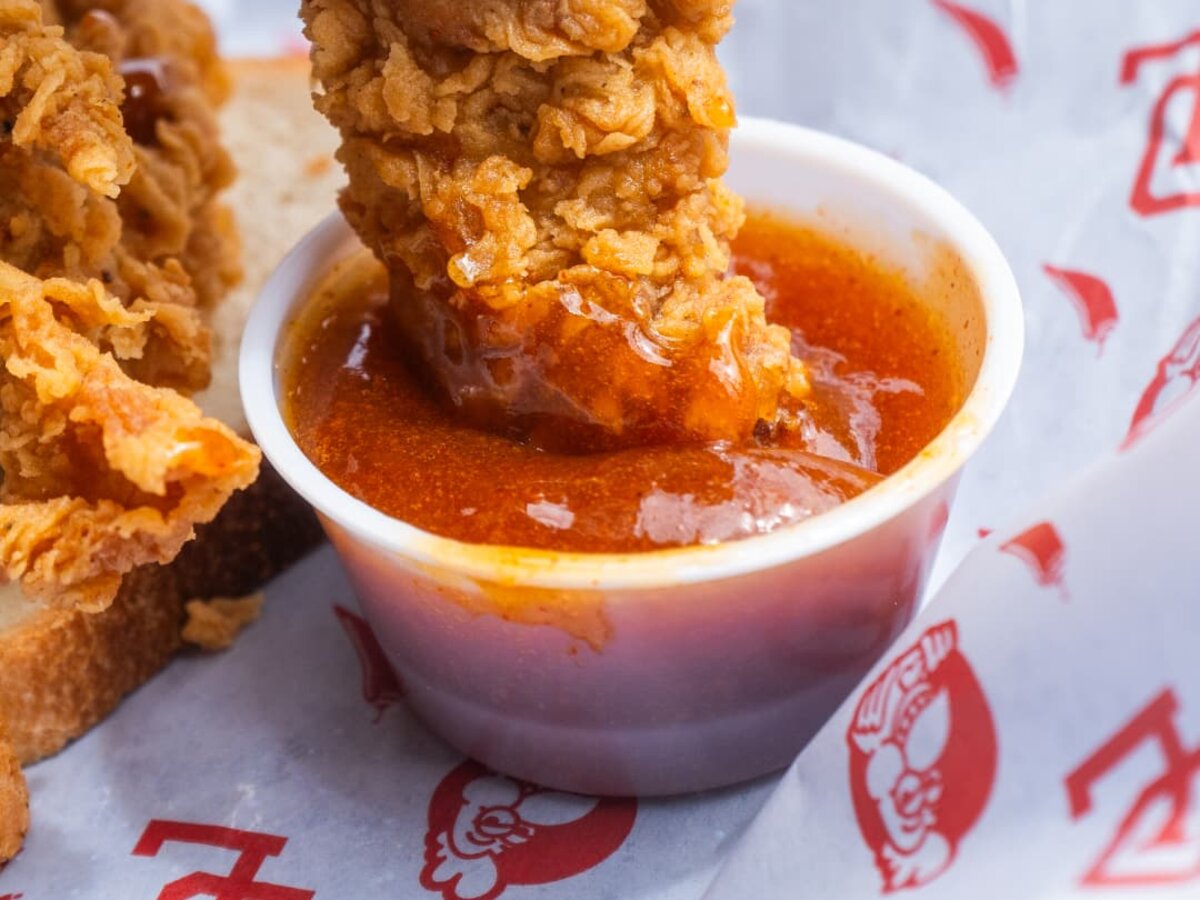 A tender being dipped into sauce